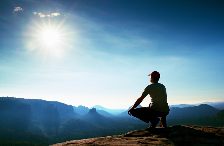 man squatting position looking at horizon