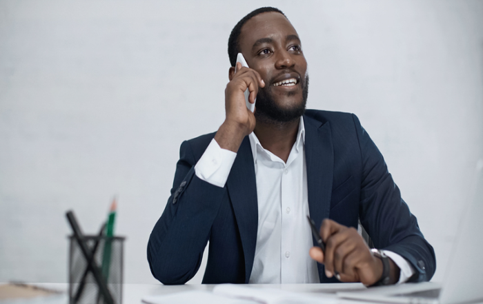 Man-sitting-at-desk-on-mobile-phone