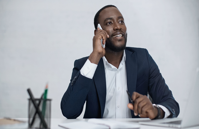 Man-sitting-at-desk-on-mobile-phone